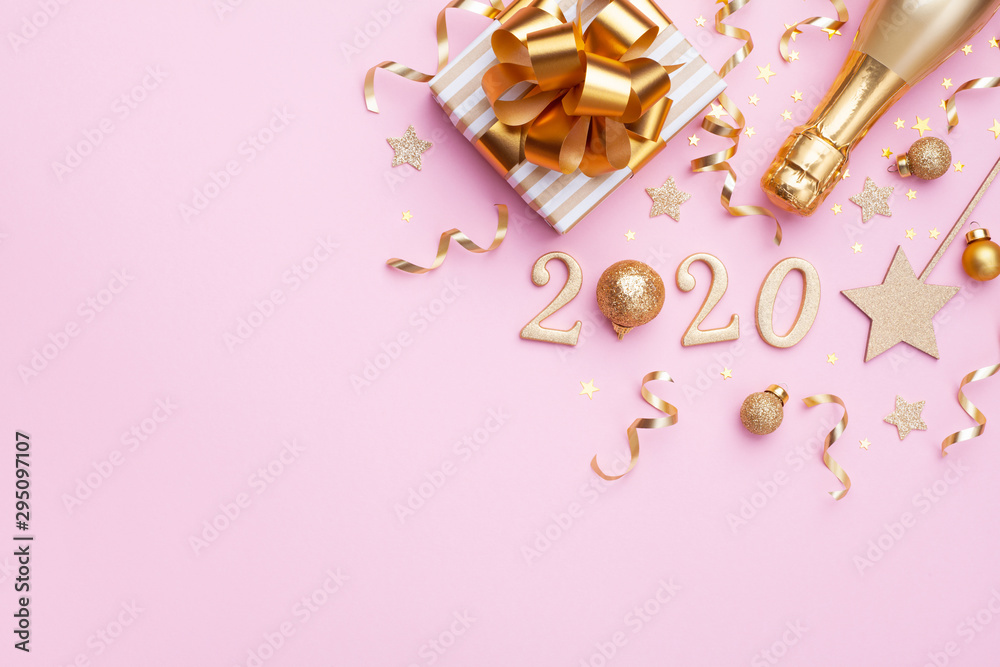 Flat lay background for Christmas and New Year. Champagne bottle, golden gift or present box, 2020 number and confetti on pink top view.