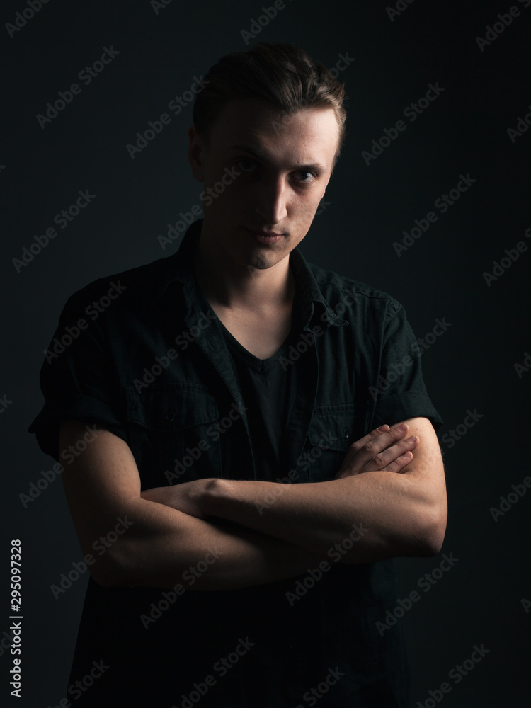 Serious young man on black background