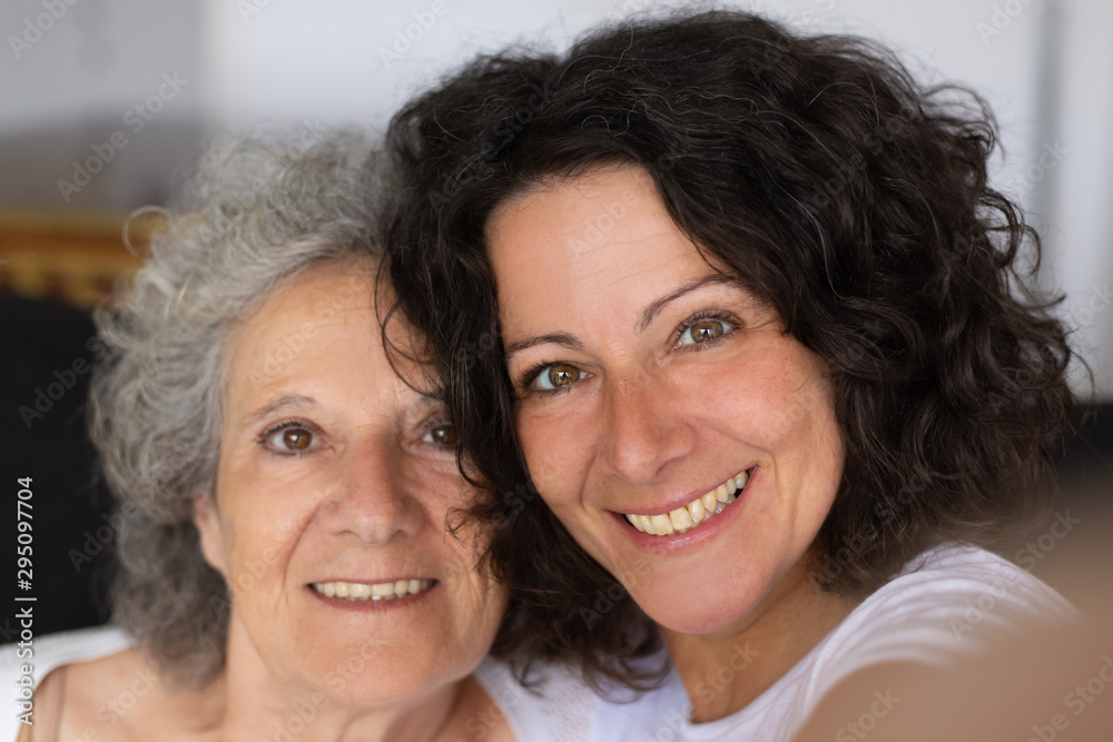 Cheerful senior mother and adult daughter taking selfie. Closeup of happy middle aged woman and elderly lady smiling at camera Family self portrait concept Cheerful senior mother and adult daughter taking selfie. Closeup of happy middle aged woman and elderly lady smiling at camera Family self portrait concept