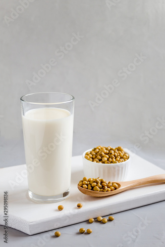 Glass with soy milk and soybeans in a plate on the table. Vegetable drink. Vegetarian food. The concept of healthy eating. Space for text.