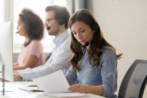 Customer support phone operator sitting at workplace holds read document