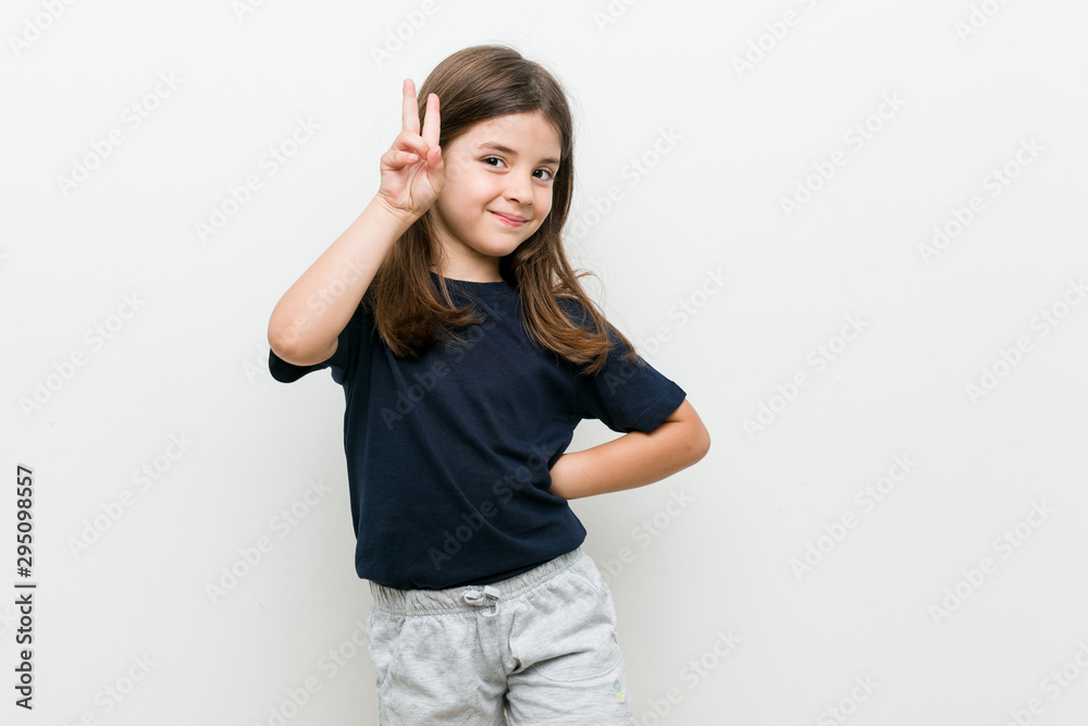 Fototapeta premium Cute little caucasian girl showing victory sign and smiling broadly.