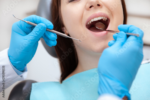 Cropped close up of a female patient with healthy teeth having dental examination by professional dentist