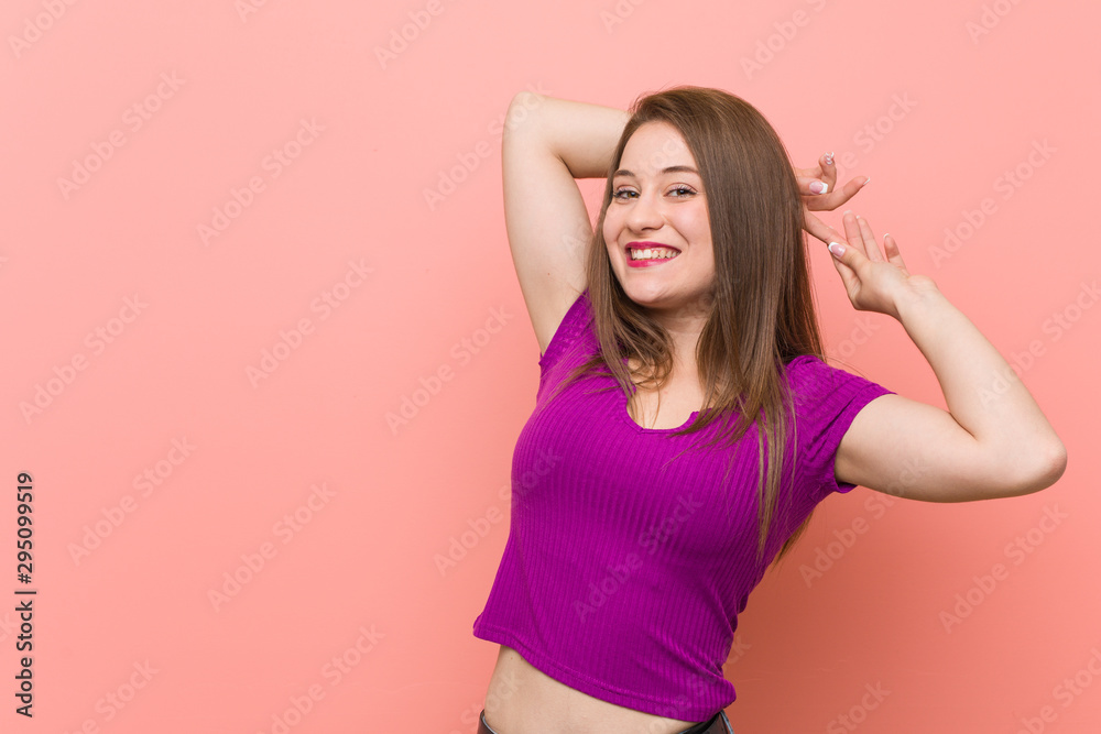Young hispanic woman against a pink wall stretching arms, relaxed position.