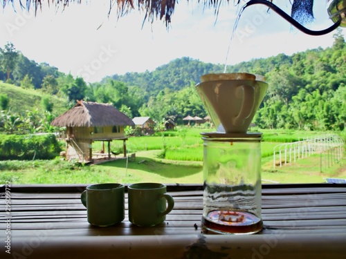 Hot water pot pouring in the dip coffee for drink with green mountain background in Chiang Mai, Thailand