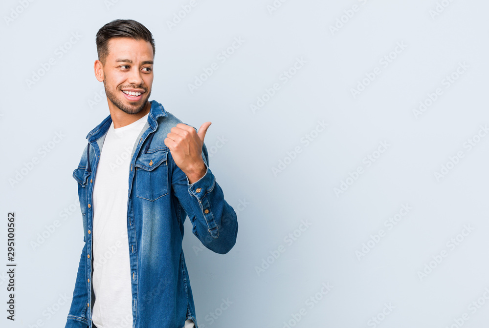 Young handsome filipino man points with thumb finger away, laughing and carefree. Young handsome filipino man points with thumb finger away, laughing and carefree.