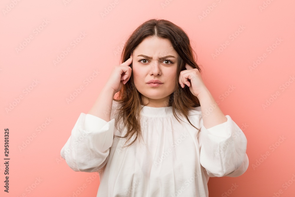 Young caucasian curvy woman standing against pink background