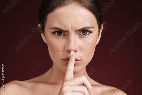 Image of confident shirtless woman holding finger at her lips