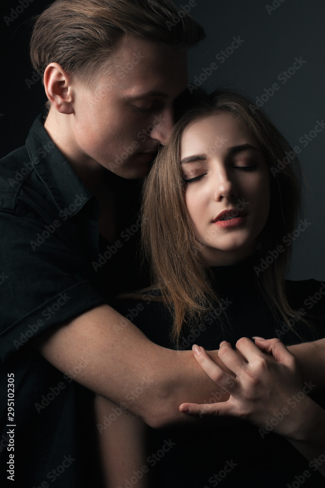 Young man and woman posing in studio. Low key.