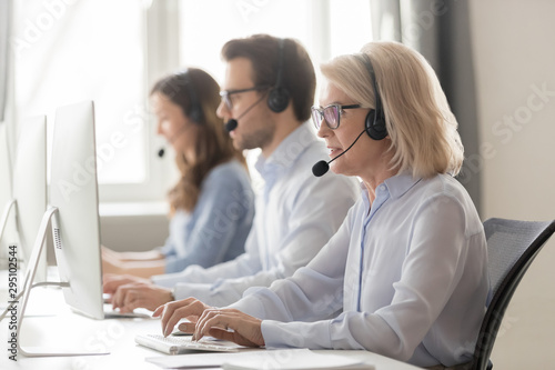 Aged call center employee sitting at workplace having busy workday