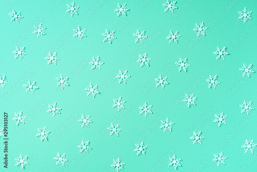 Winter pattern made of white snowflakes on trendy green background. Top view. Flat lay. Winter composition. Christmas, new year concept.