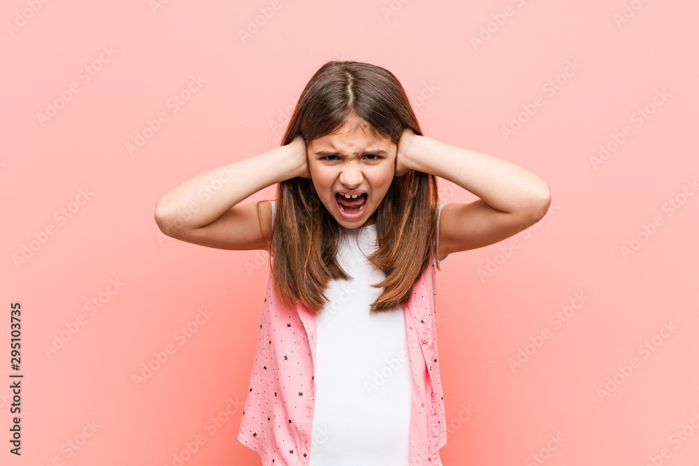 Cute little girl covering ears with hands trying not to hear too loud sound.