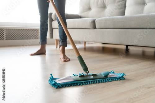 Woman housewife holding mop cleaning floor at home, close up