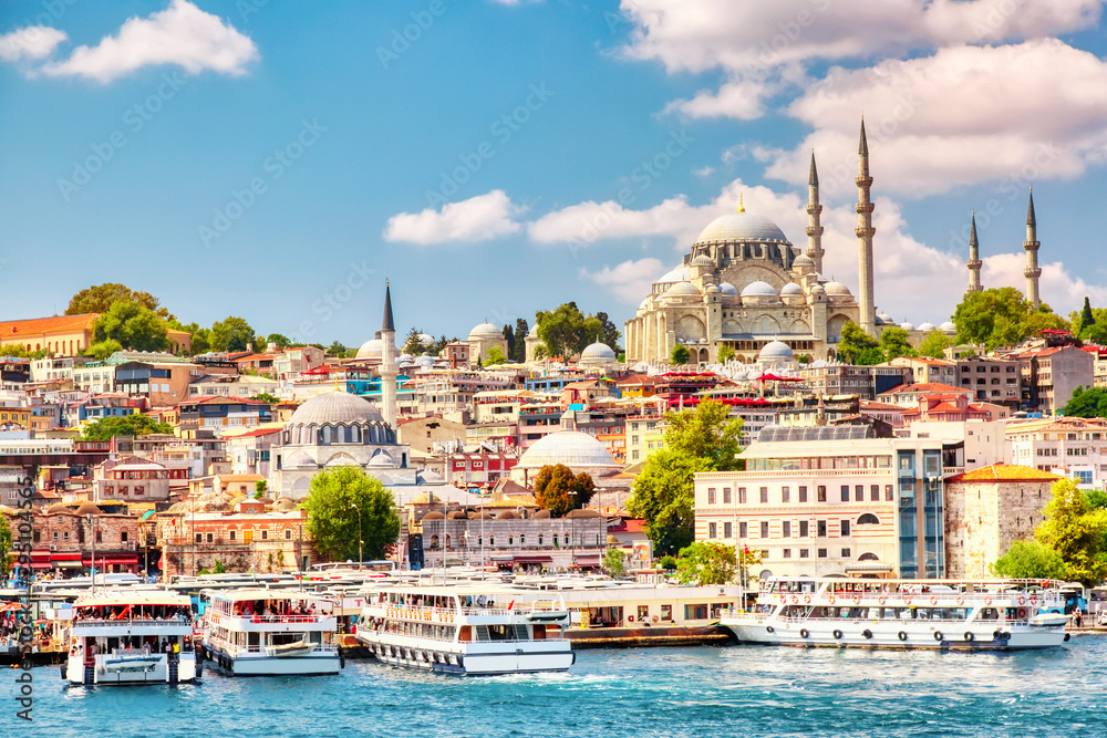 Naklejka premium Turystyczne statki wycieczkowe w zatoce Golden Horn w Stambule i widok na meczet Sulejmana Wspaniałego z dzielnicą Sultanahmet na tle błękitnego nieba i chmur. Stambuł, Turcja w słoneczny letni dzień.