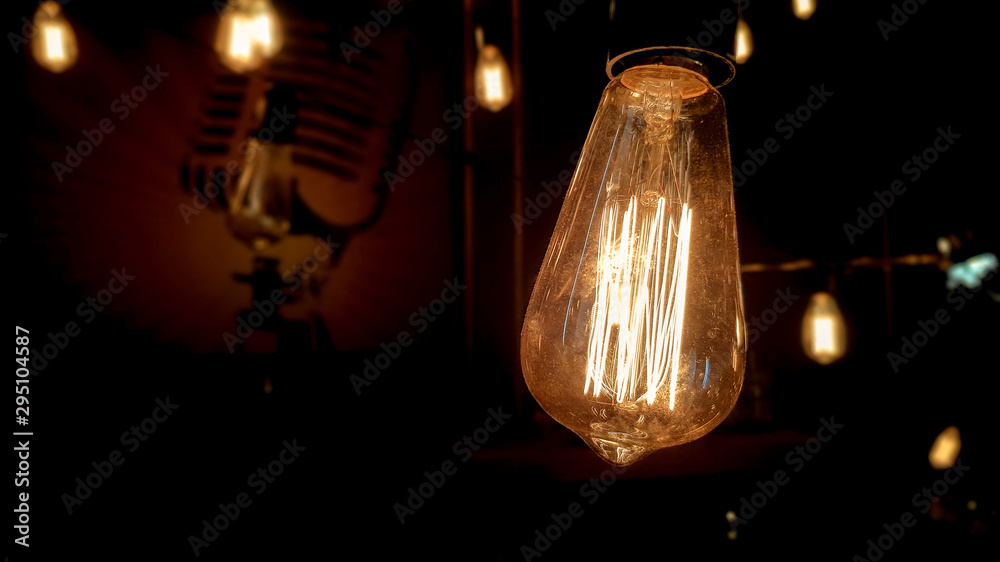 Lighting decor. Vintage hanging edison light bulb on a dark background. Old dusty light bulbs glowing in the dark. A lamp inside a decorative glass lamp. Light begins to appear and glow in the center.