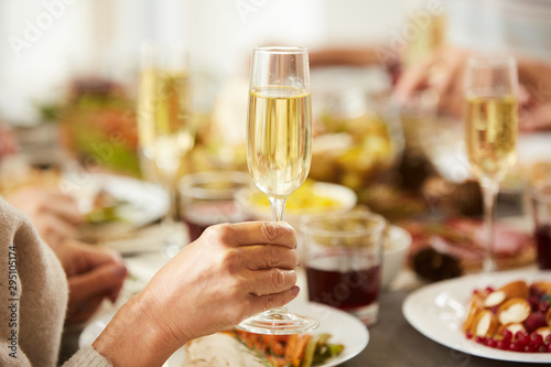 Close-up of female hand holding glass with champagne while have dinner at the table