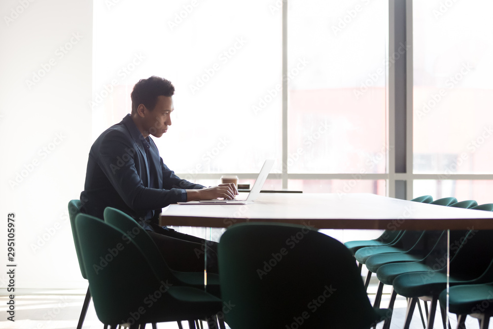 Focused african businessman working on laptop sit at conference table