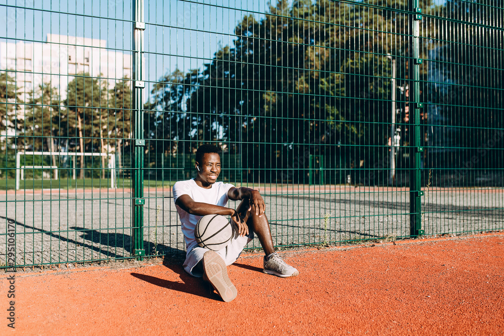 A strong African-American rests after a workout, listening to music in headphones A strong African-American rests after a workout, listening to music in headphones