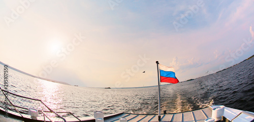 View of waving Russian flag on ship. Against the background of water and blue peaceful sky. The concept of patriotism and love for their homeland.