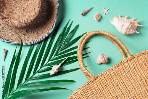 Summer travel concept with women straw bag, hat, palm leaves, shells on trendy yellow and green background. Top view. Copy space photo