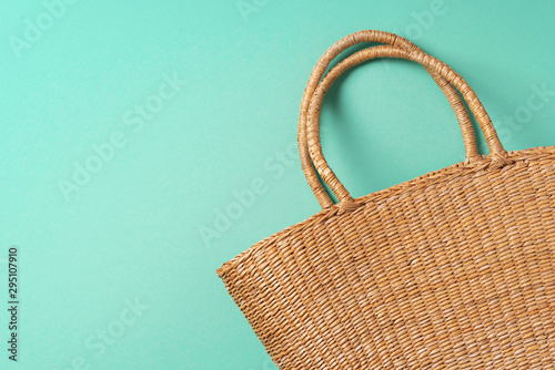 Women's straw bag on trendy green background. Top view. Copy space. Summer travel concept. Sustainable lifestyle. Zero waste, plastic free concept.