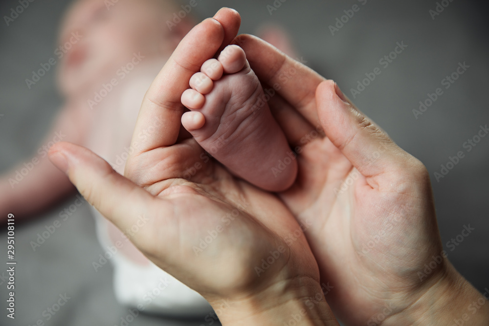 Mother holding newborn baby feet in hands. Mom taking care about infant child after taking bath. Parents childcare. Children healthcare and happy family Mother holding newborn baby feet in hands. Mom taking care about infant child after taking bath. Parents childcare. Children healthcare and happy family