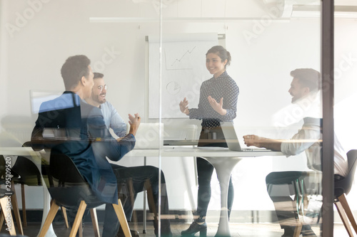 Smiling indian female speaker give flip chart presentation in boardroom