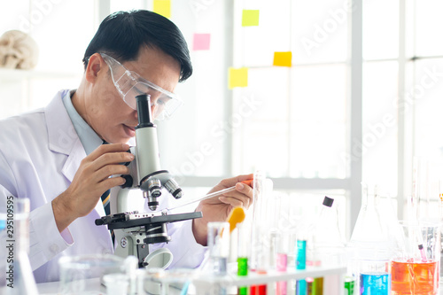 Asian male scientist look through the microscope in the laboratory.