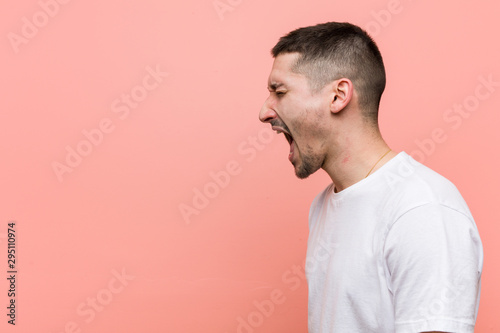 Young casual man shouting towards a copy space