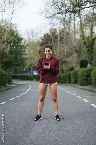 Sporty cheerful young woman taking a running rest for checking workout goals on smartphone app. © Dirima