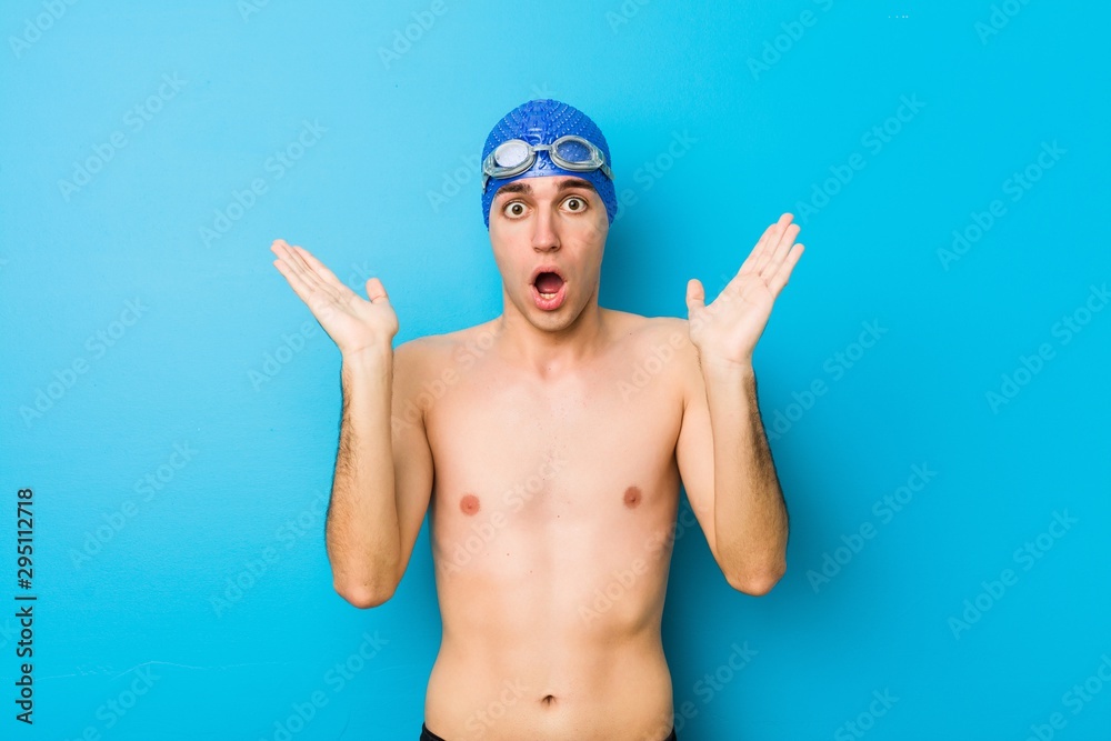 Young swimmer man surprised and shocked. - obrazy, fototapety, plakaty 