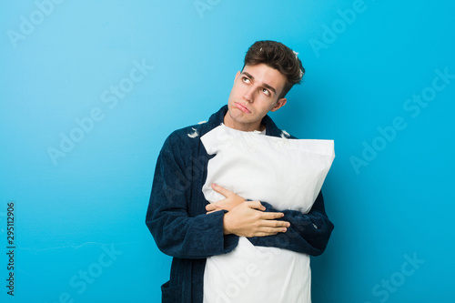 Teenager caucasian tired man holding a pillow