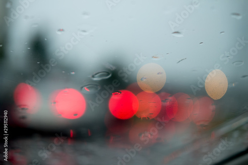 Blurred out of focus view rain drops on car glass focus on the road way