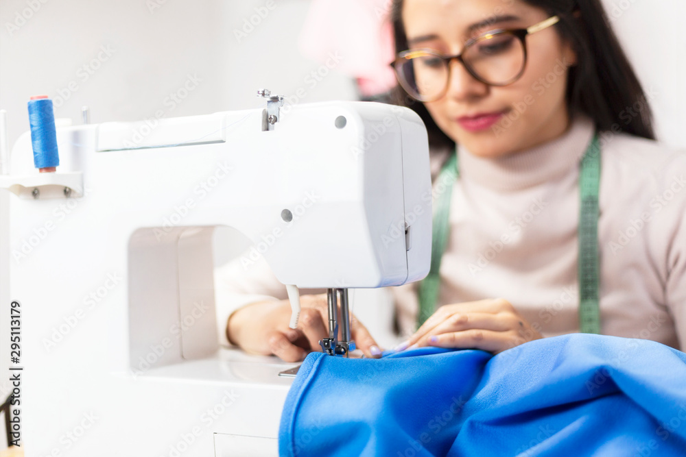 Detail of fashion designer hands working on sewing machine- young Hispanic entrepreneur