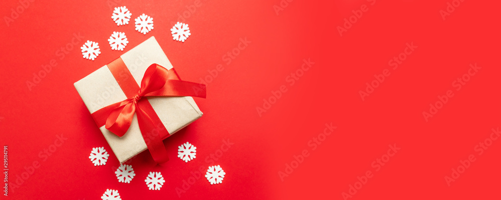 Festive christmas composition with snowflakes and gift box on red background. Winter concept. Flat lay, top view, copy space Festive christmas composition with snowflakes and gift box on red background. Winter concept. Flat lay, top view, copy space