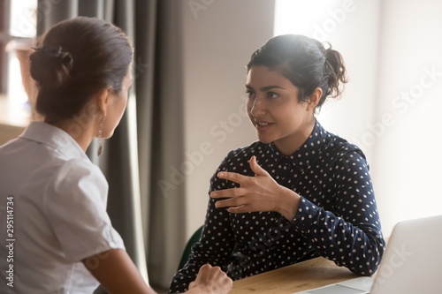 Foto Serious indian mentor worker talk to female colleague teach intern
