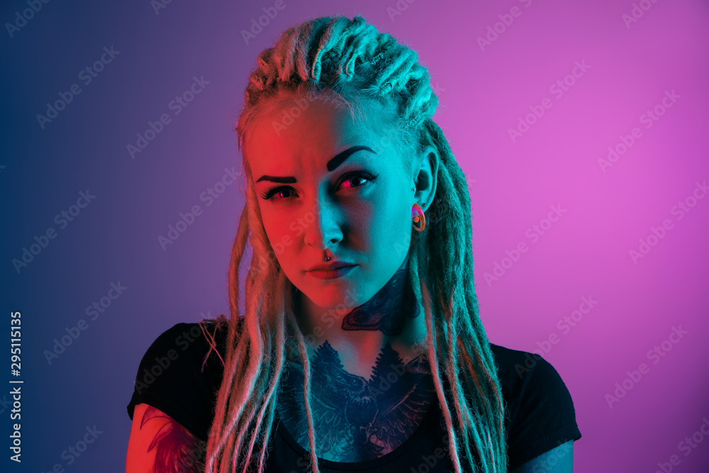 Caucasian young woman's portrait on gradient background in neon light. Beautiful female model with unusual look. Concept of human emotions, facial expression, sales, ad. Asking a question, uncertain. Caucasian young woman's portrait on gradient background in neon light. Beautiful female model with unusual look. Concept of human emotions, facial expression, sales, ad. Asking a question, uncertain.