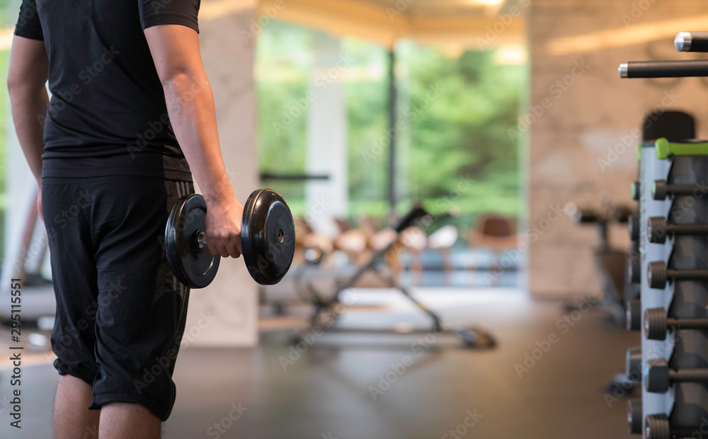 Fototapeta premium Man lifting dumbbell weights stand in fitness