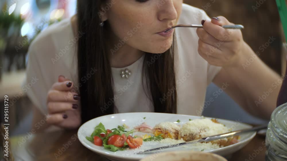 beautiful girl eats pancakes with ham, cheese, greens and tomatoes in cafe. beautiful girl eats pancakes with ham, cheese, greens and tomatoes in cafe.