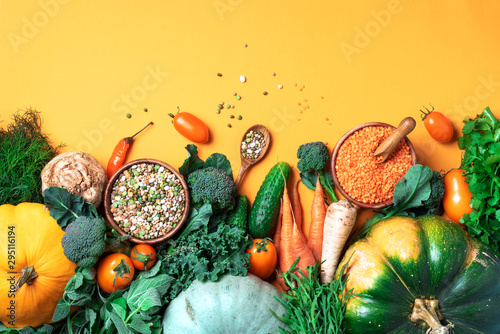 Organic vegetables, lentils, beans, raw ingredients for cooking on trendy yellow background. Healthy, clean eating concept. Vegan or gluten free diet. Copy space. Top view. Food frame photo