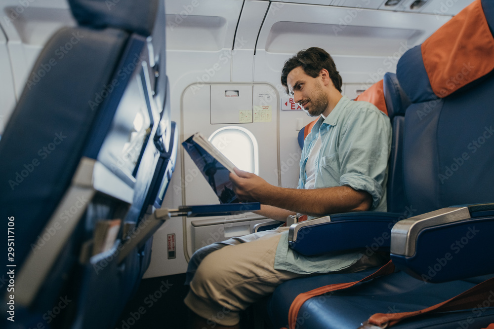The guy flies in an airplane with a magazine in his hands