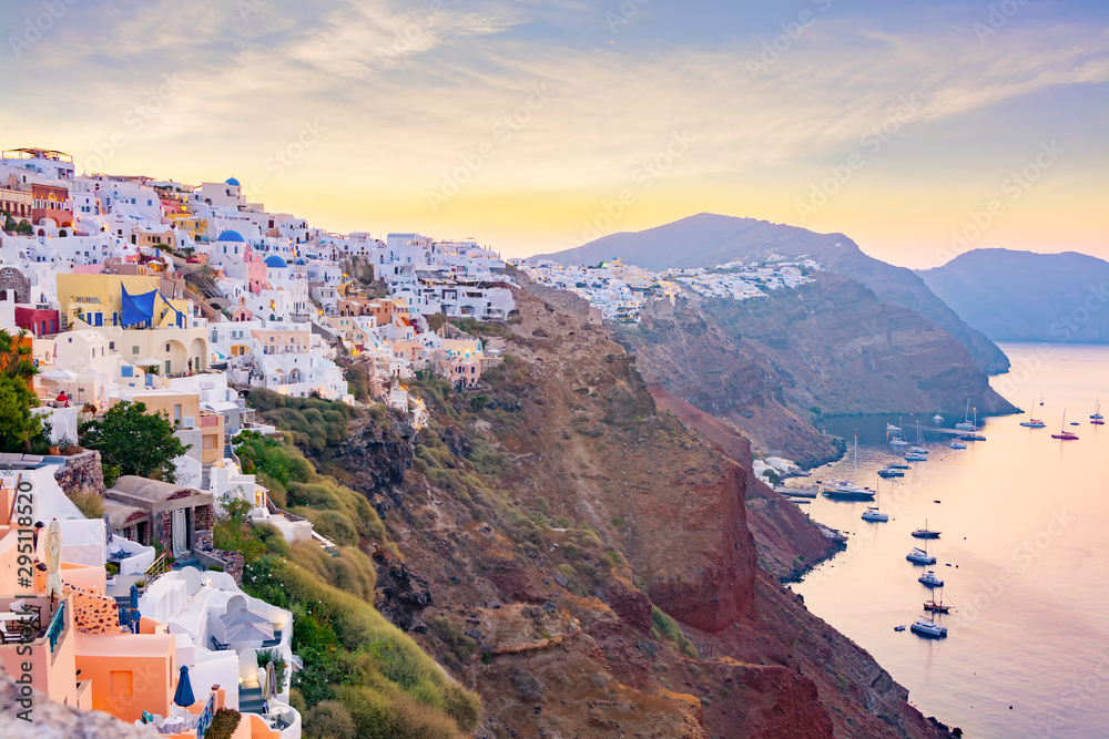 Picturesque cityscape of Oia village on Santorini Island with traditional white architecture over the Caldera mountains in Aegean sea at sunset,  Greece. Scenic travel background.