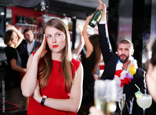 Offended woman on background with drunk man