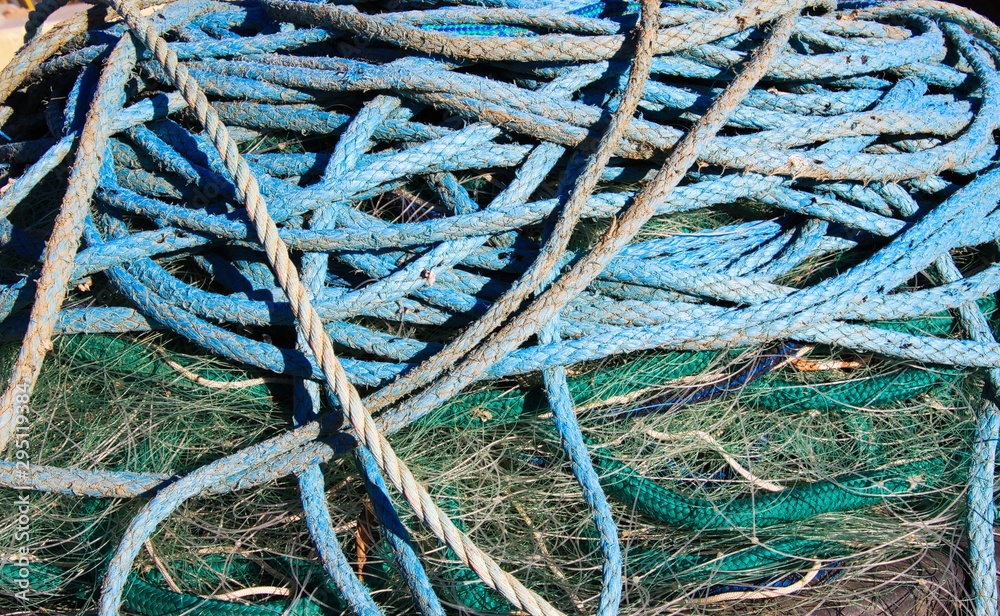 Close up of pile of blue ship ropes on green isolated fishing net