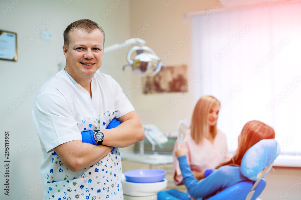 A portrait of a dentist with his team working in the background. A portrait of a dentist with his team working in the background.