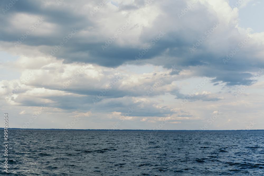 Beautiful white clouds over water surface of wide river