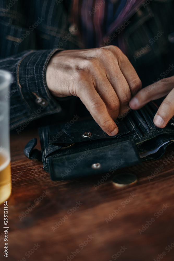 Hands holding  wallet between beer glasses