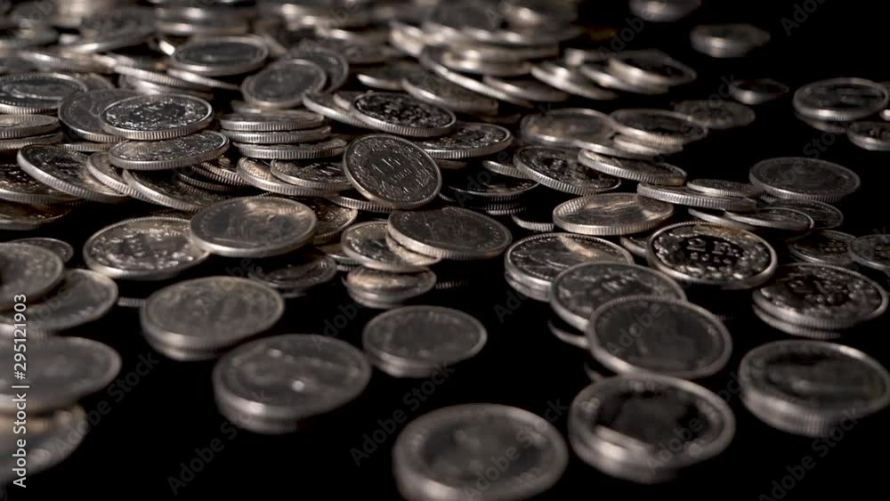 Slow motion shot of Swiss coins thrown on a reflecting table in front of black background Slow motion shot of Swiss coins thrown on a reflecting table in front of black background