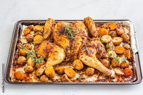 Spatchcocked barbecue chicken with Potatoes on a Baking Tin on White Background, Directly Above Photo. Oven Roasted .Spatchcock Chicken on White Background. photo