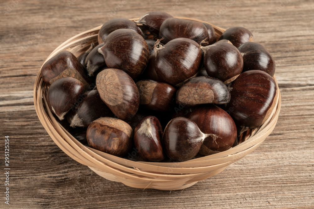 Obraz premium raw chestnuts in basket on a wooden table